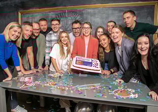 group of Fifth Ring employees celebrating Great Place to Work with a cake